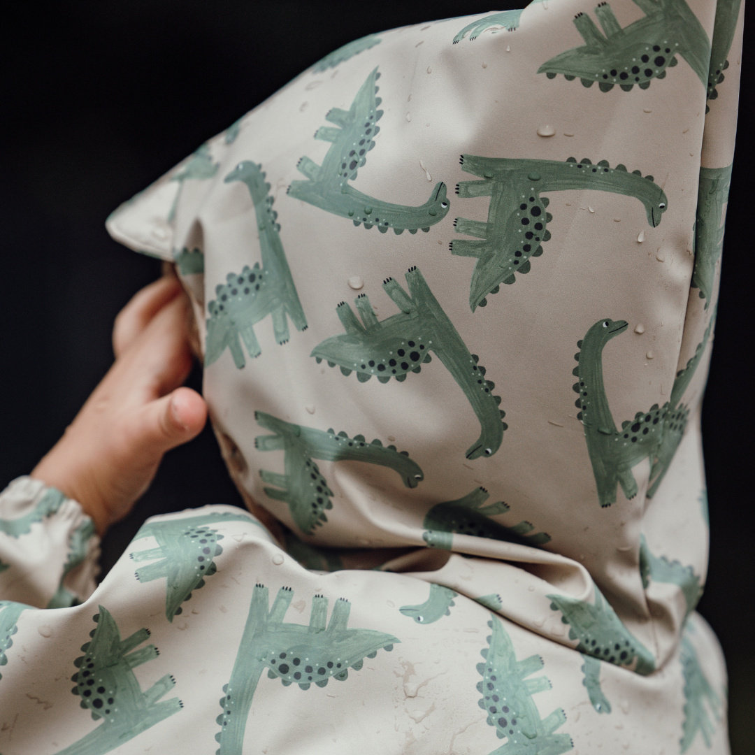 Detailaufnahme des wasserabweisenden Dino-Stoffs eines Kinderponchos – nachhaltige Regenmode mit Reflektor von Joni Studio