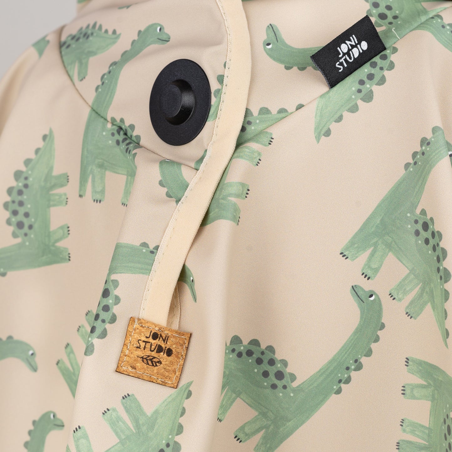 Nahaufnahme des Magnetknopf-Verschlusses am Dino-Regenponcho – kindgerechtes Design von Joni Studio mit Korklabel