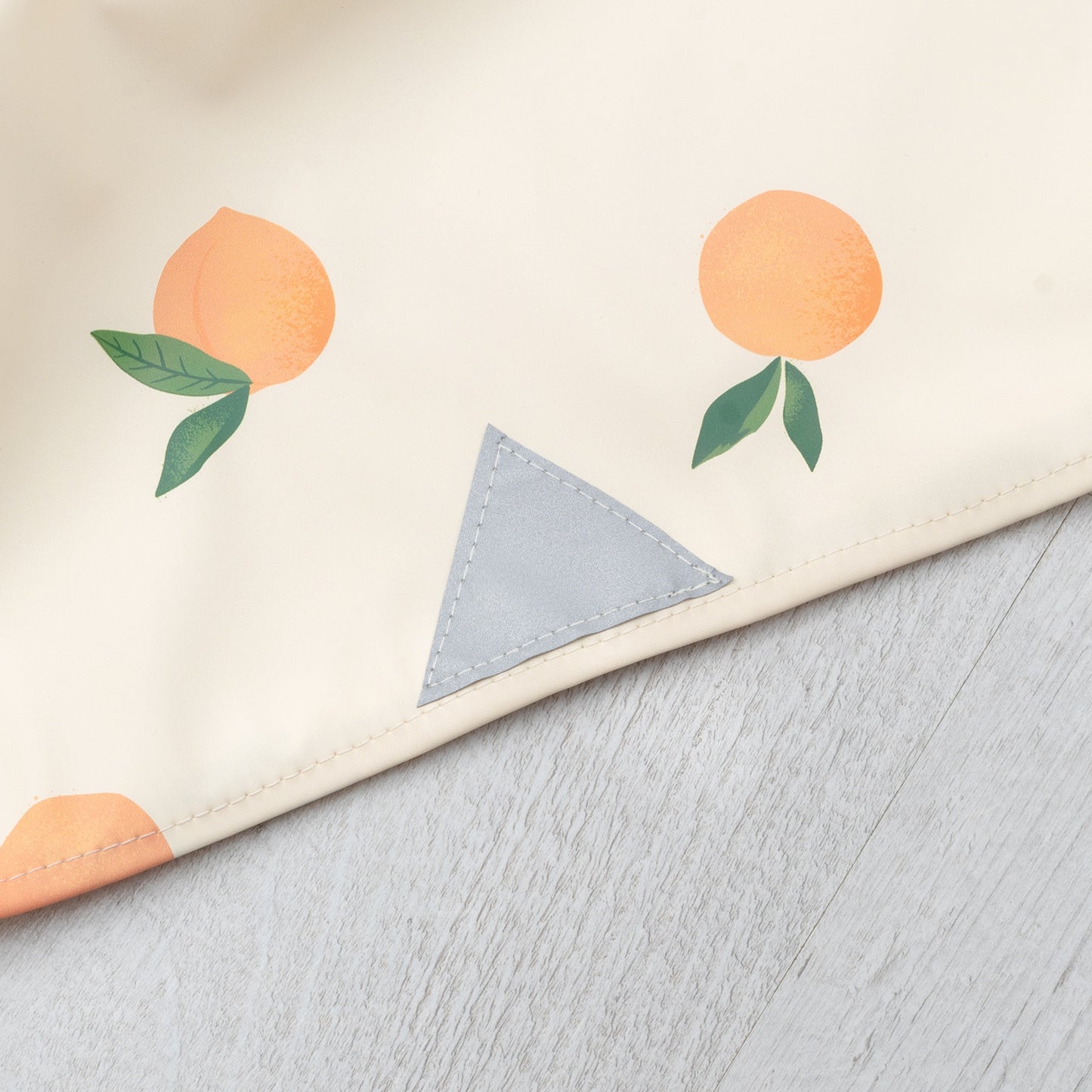 Detail des reflektierenden Dreiecks am Saum des Kinderregenponchos – kombiniert mit Magnetknopf für schnelles An- und Ausziehen.
